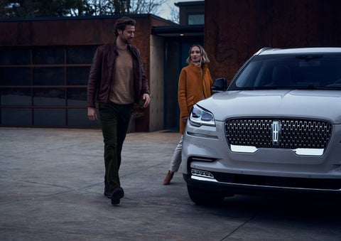 A man and a woman approaching a 2024 Lincoln Aviator® SUV, which illuminates certain lights when they are close | Al Packer Lincoln in West Palm Beach FL