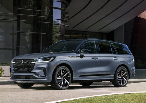 A gray 2025 Lincoln Aviator® SUV is parked outside a modern building showcasing the driver’s side of the vehicle. | Al Packer Lincoln in West Palm Beach FL