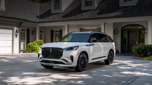 A white 2026 Lincoln Aviator® SUV is parked in the driveway of a luxury home. | Al Packer Lincoln in West Palm Beach FL