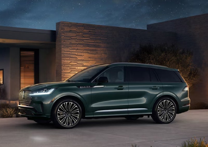 A green 2027 Lincoln Aviator® SUV is parked outside a contemporary home. | Al Packer Lincoln in West Palm Beach FL