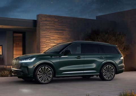 A green 2027 Lincoln Aviator® SUV is parked outside a contemporary home. | Al Packer Lincoln in West Palm Beach FL