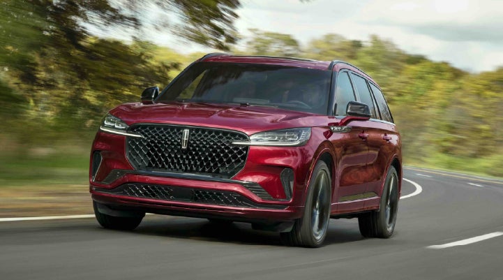 A 2027 Lincoln Aviator® SUV is being driven on a country road | Al Packer Lincoln in West Palm Beach FL