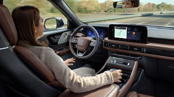 A 2027 Lincoln Aviator® SUV is being driven hands-free on a highway lined with trees. | Al Packer Lincoln in West Palm Beach FL