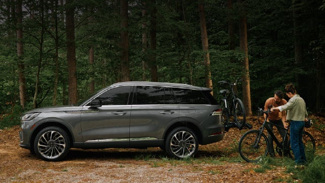 A father and son load e-bikes on a bike rack attached to a 2027 Lincoln Aviator® SUV. | Al Packer Lincoln in West Palm Beach FL