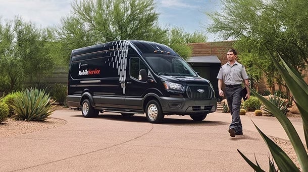 A Mobile Service expert walking toward the customer while the mobile service vehicle is parked behind