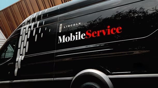 A black mobile service vehicle with white and red print 