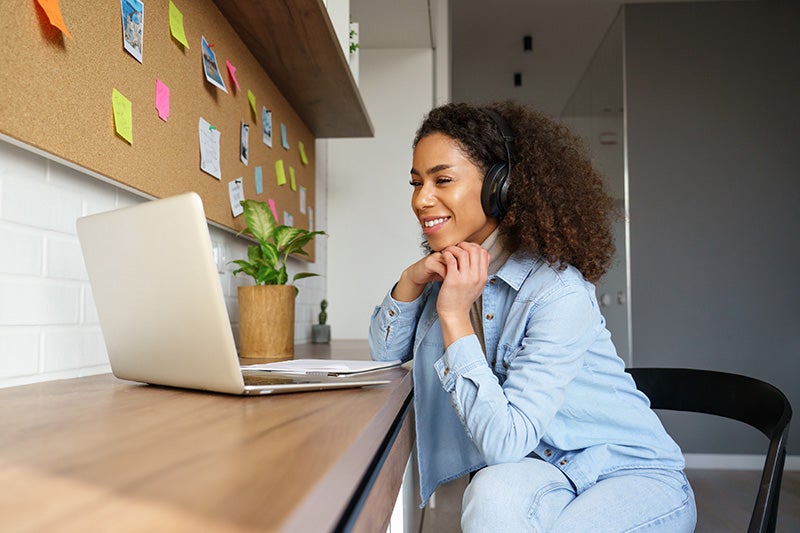 A woman wearing headphones, sitting at her desk in front of a computer